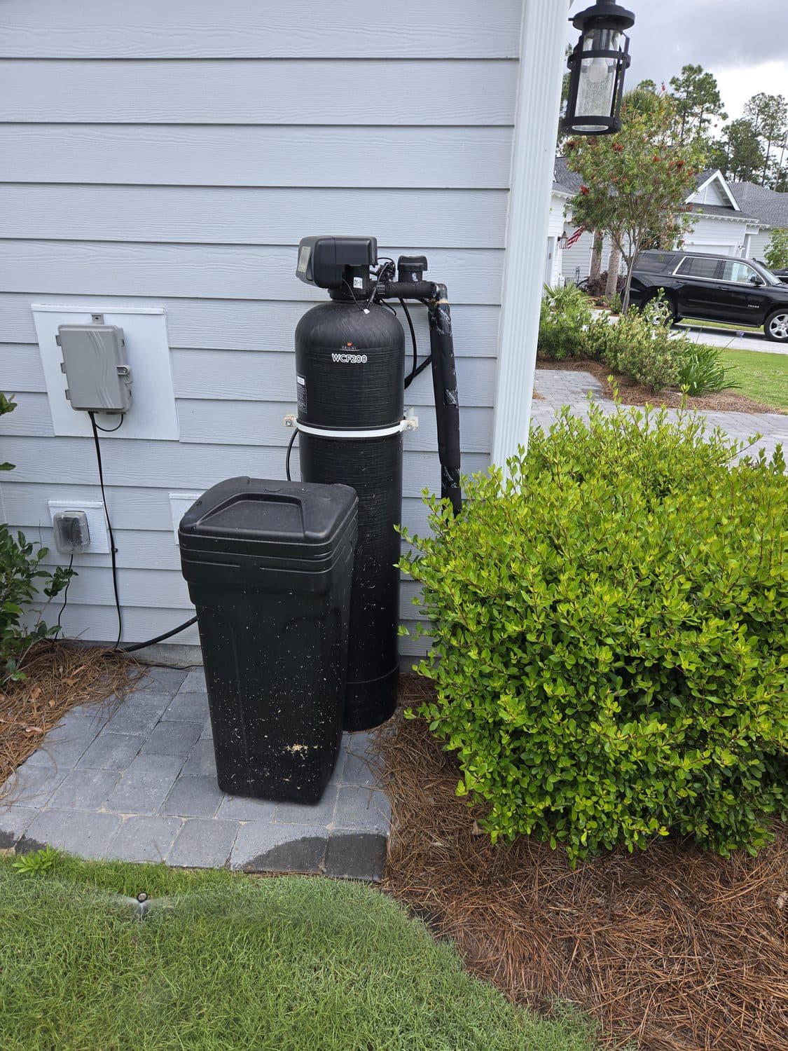 D'Pure whole-home water filter and softener installed beside a home